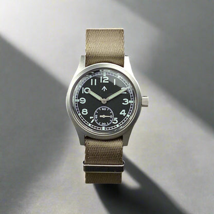 Aeschbach x Enoksen 'Fly' E03/T Dirty Dozen Automatic watch, 36mm, black dial, shown with a Khaki Seatbelt NATO strap.