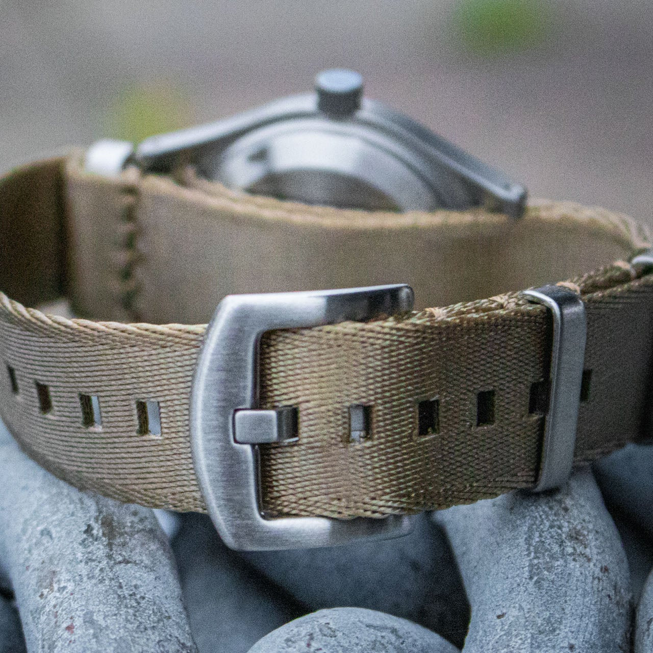 The Aeschbach x Enoksen 'Fly' E03/T watch displayed with a khaki seatbelt NATO strap.